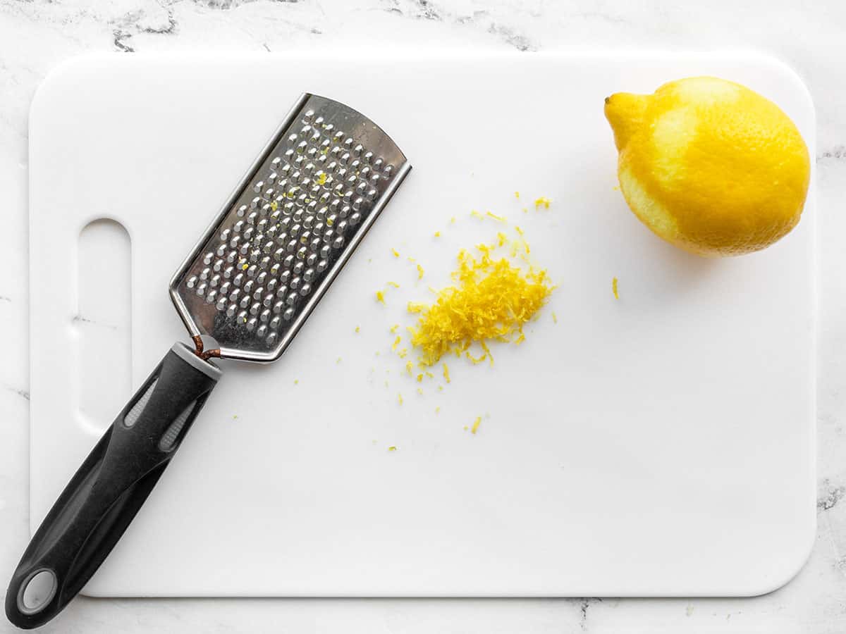 Zested lemon on a cutting board with a small-holed cheese grater