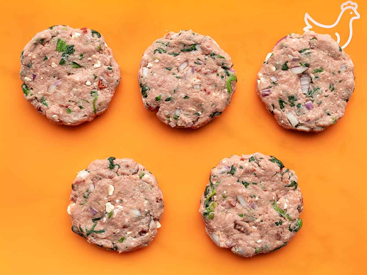 Shaped Turkey Burgers on an orange cutting board