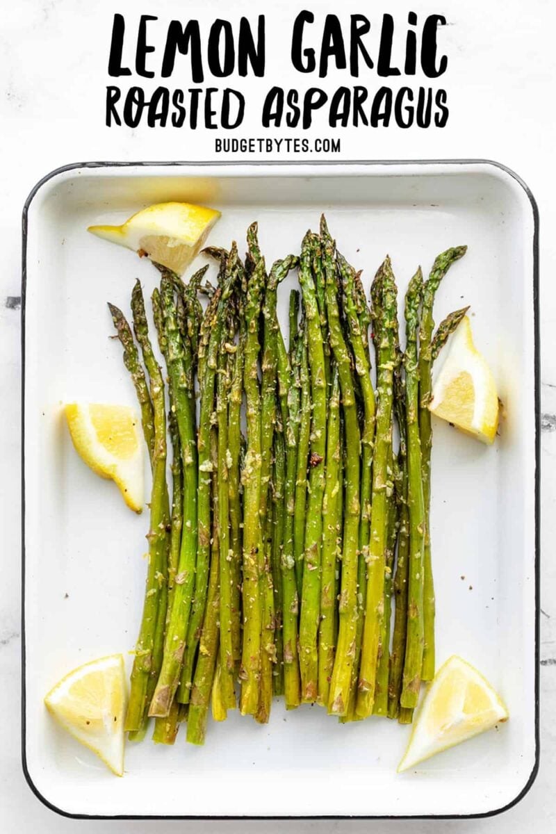 Roasted asparagus on a white sheet pan with lemon wedges, title text at the top