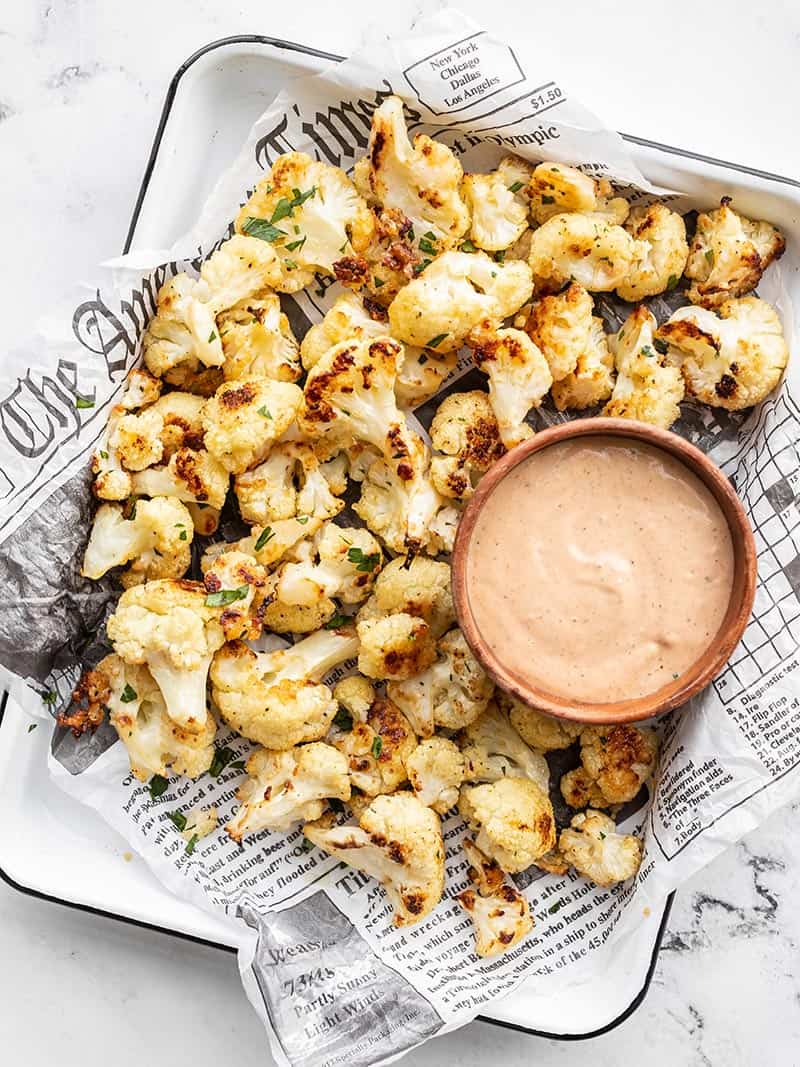Overhead of Garlic Parmesan Roasted Cauliflower on a tray with a bowl of dipping sauce