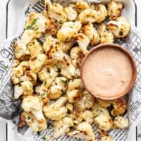 Overhead of garlic parmesan roasted cauliflower on a tray with a bowl of dip