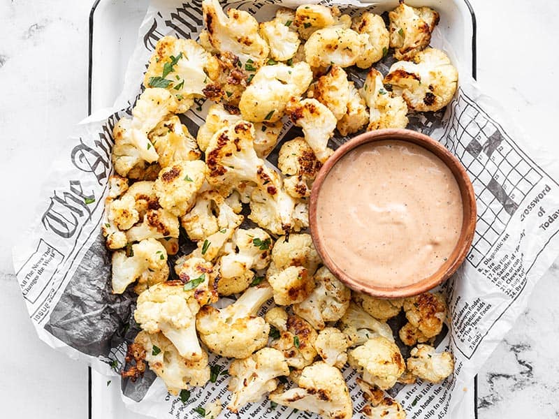 Overhead of garlic parmesan roasted cauliflower on a tray with a bowl of dip