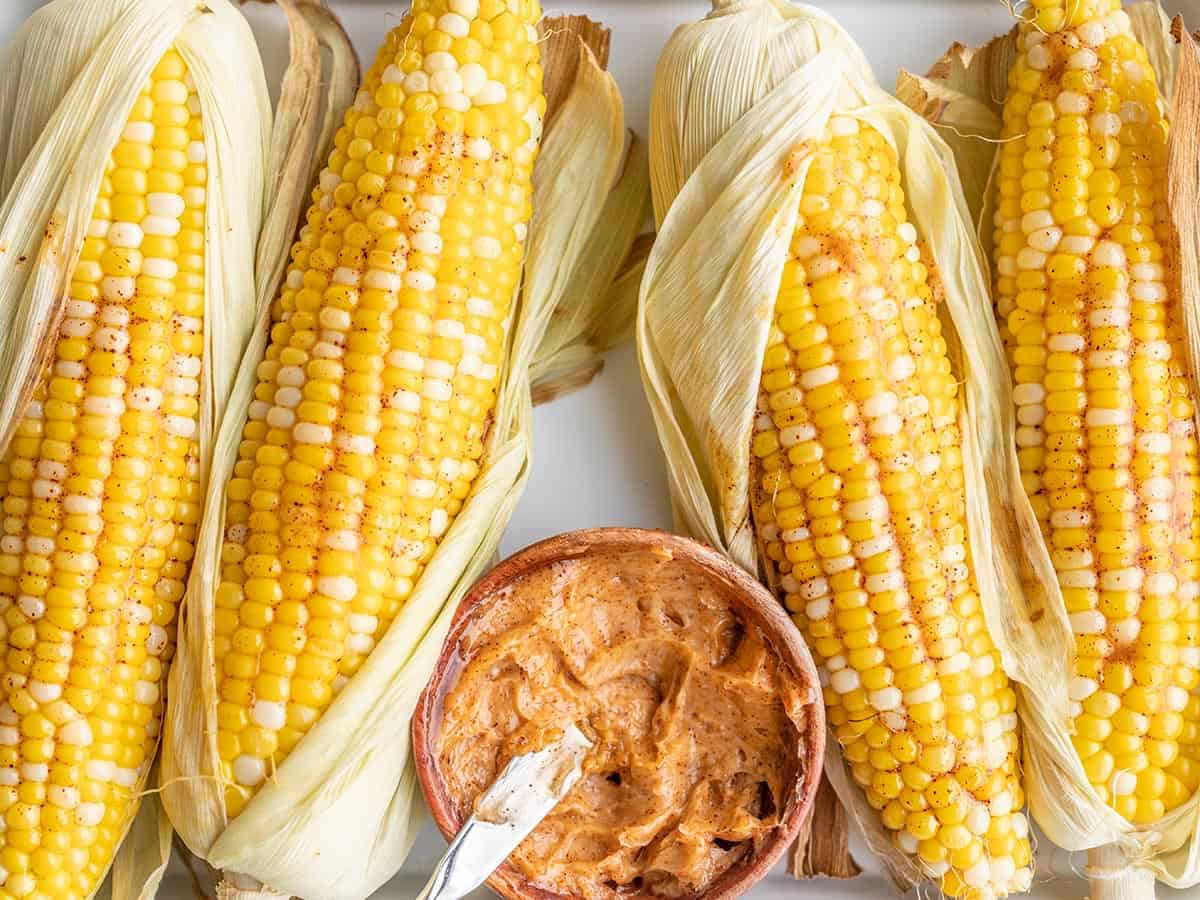 Close up of oven roasted corn with a bowl of honey chili butter