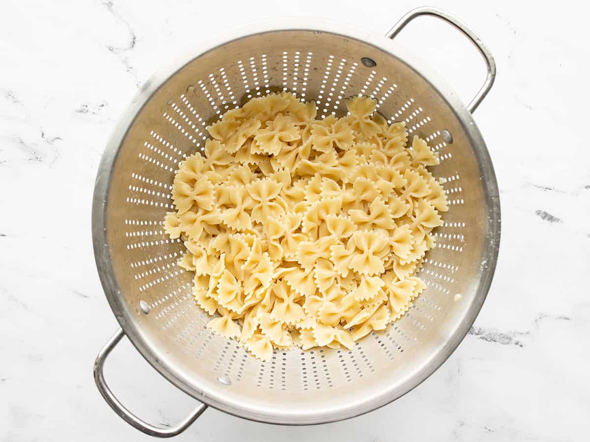 Cooked bowtie pasta in a metal colander