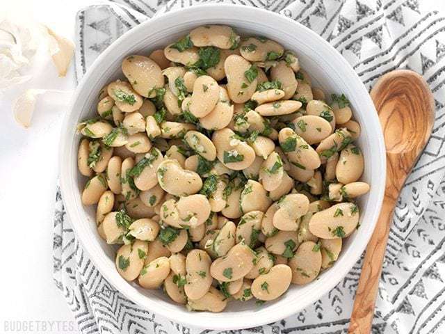 Top view of Marinated White Beans with wooden serving spoon on the side 