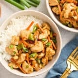 Overhead view of two bowls of kung pao chicken with rice.
