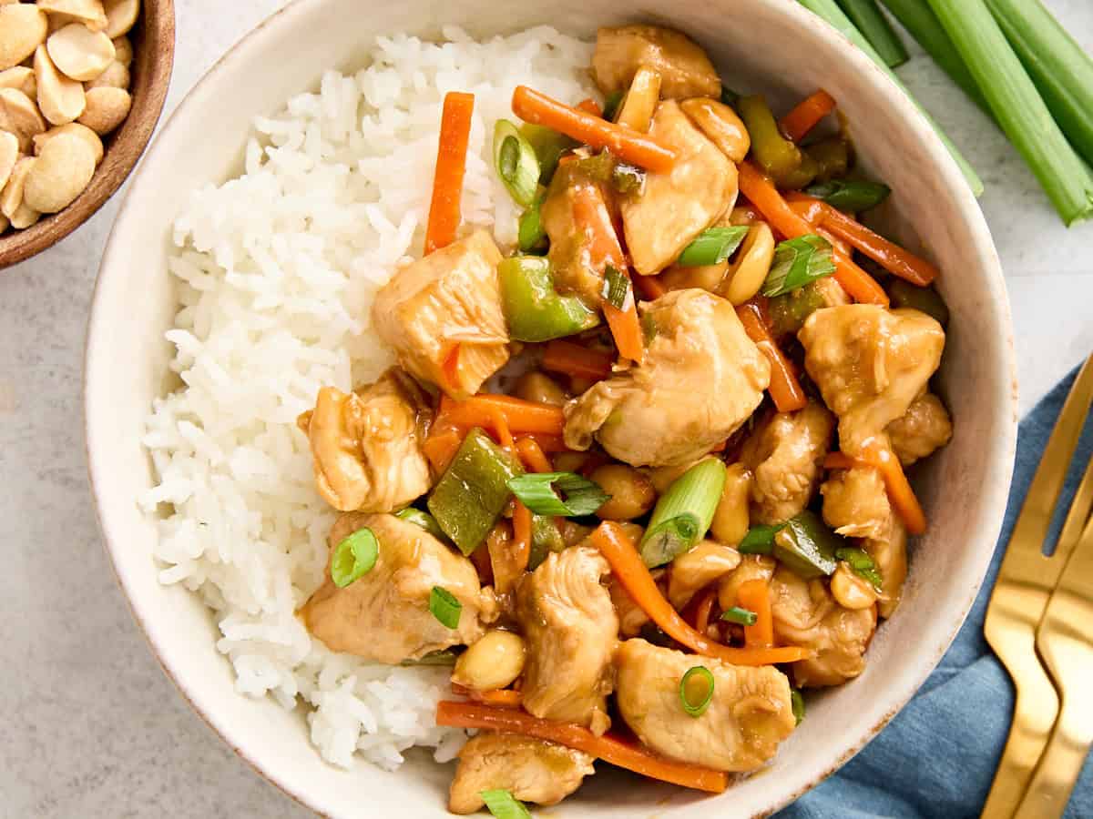 Overhead close up of homemade kung pao chicken in a bowl with cooked rice.