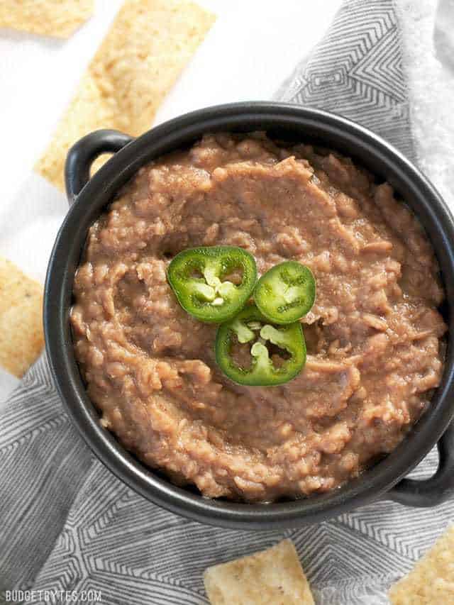 A bowl full of slow cooker (not) Refried Beans ready for dipping. Topped with sliced jalapeño 