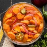 Overhead view of spicy pickled carrots in a glass bowl.