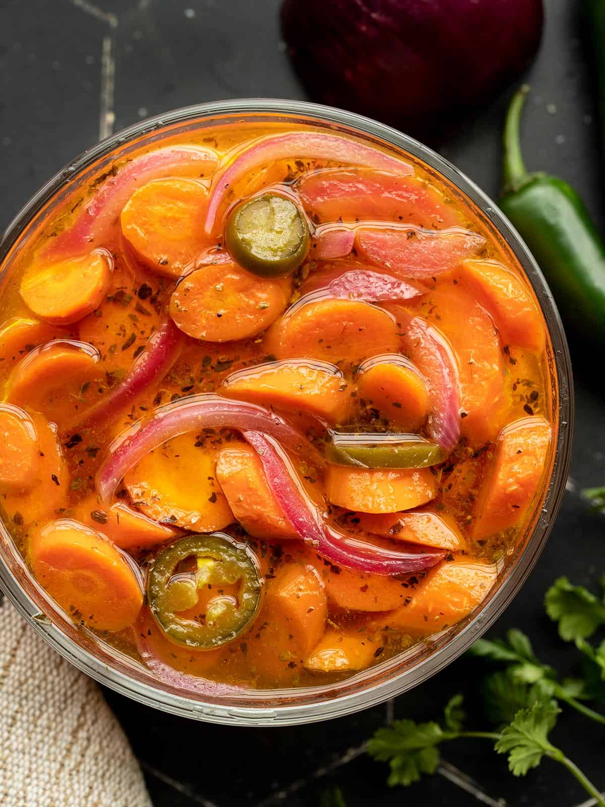 Overhead view of a glass bowl full of spicy pickled carrots