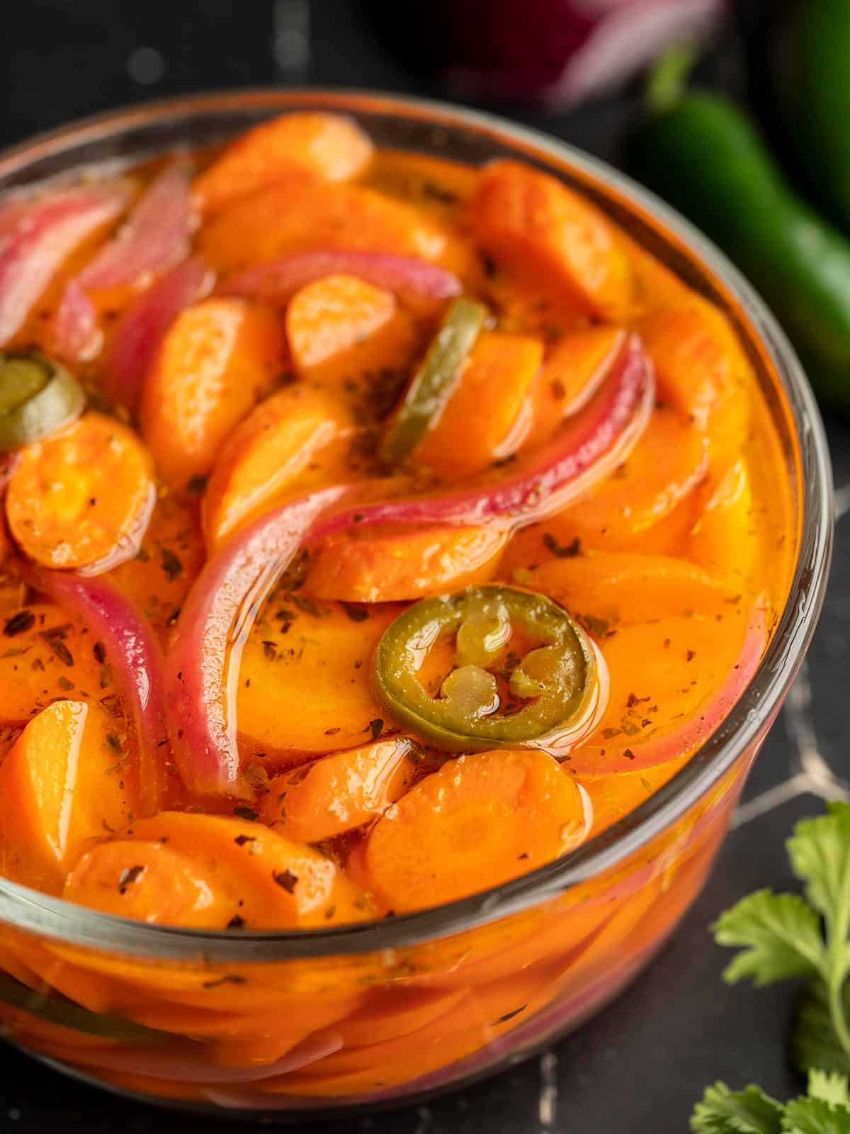 side view of a glass bowl full of spicy pickled carrots.
