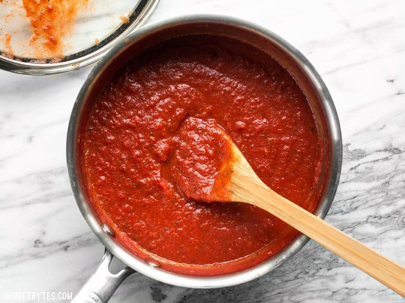 Finished Thick and Rich Pizza Sauce with a wooden spoon in the pot. 