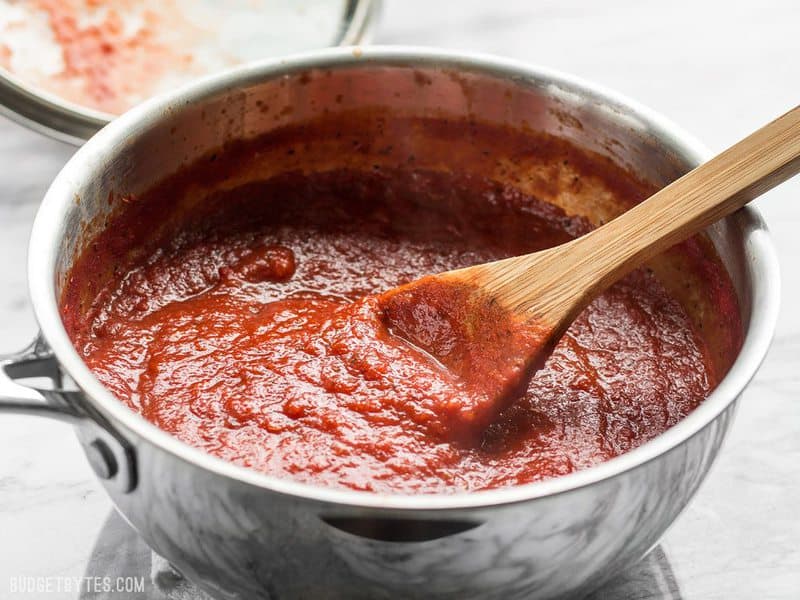 Front view of a pot of Thick and Rich Pizza Sauce with a wooden spoon in the pot.