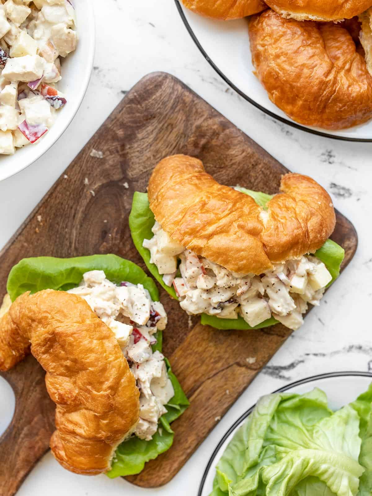 Chicken salad sandwiches made with croissants on a wooden cutting board