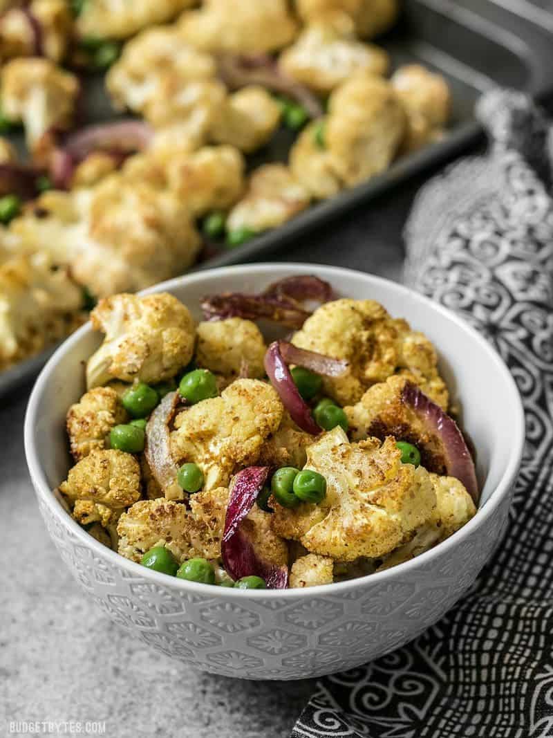 A bowl of Curry Roasted Cauliflower with the sheet pan behind it.