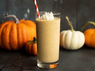 side view of pumpkin smoothie, pumpkins behind it