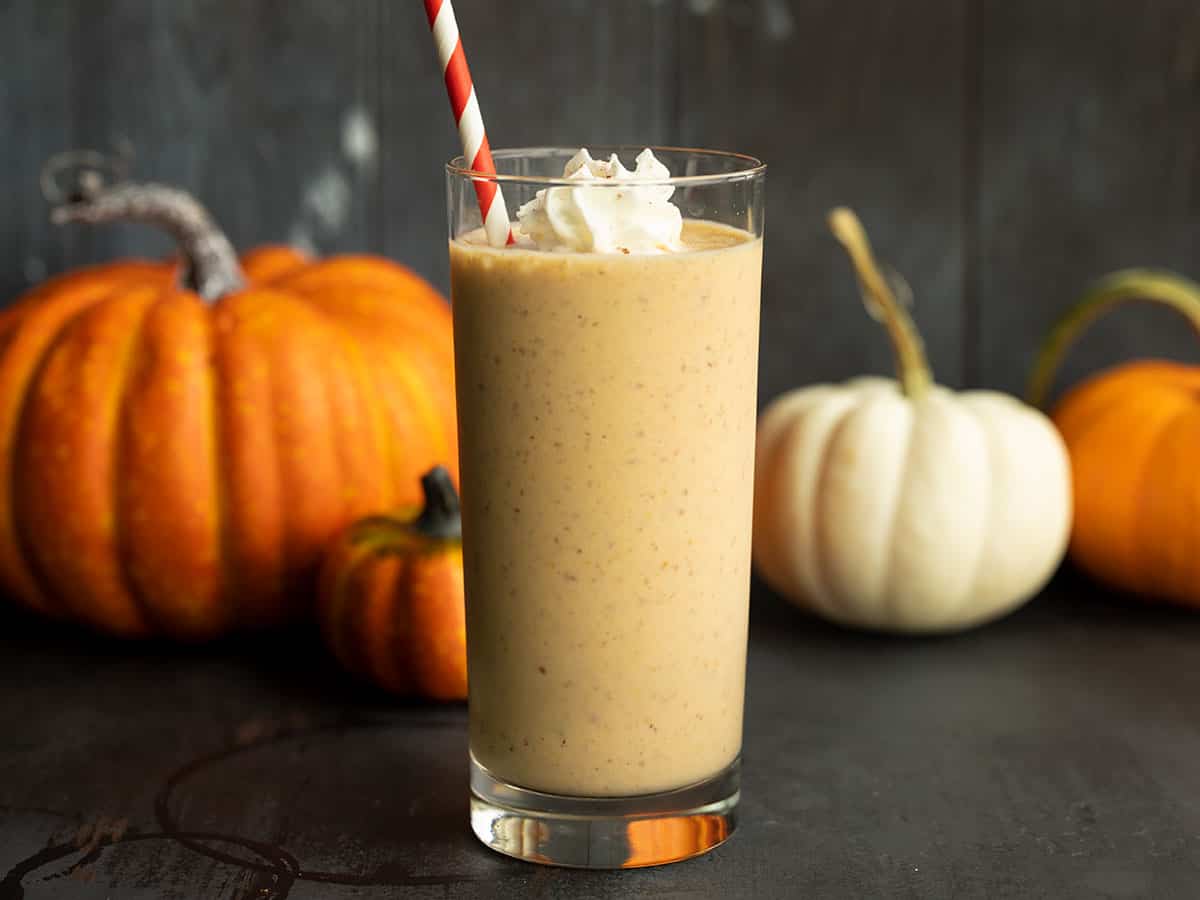 side view of pumpkin smoothie, pumpkins behind it