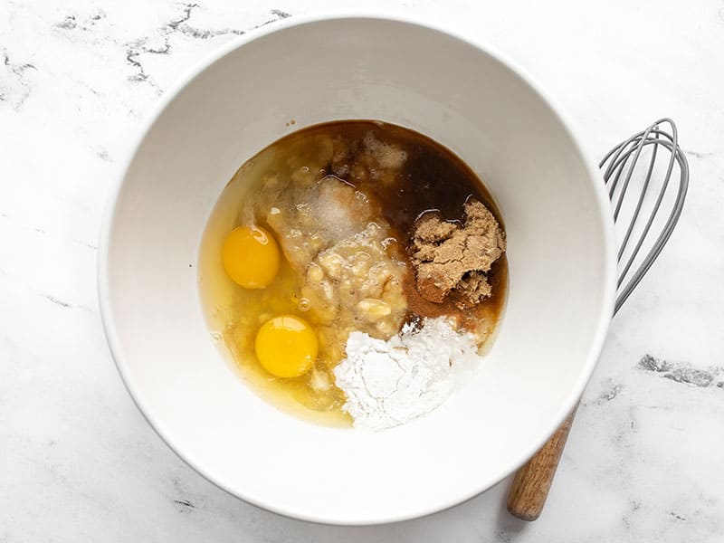 Mashed bananas in a bowl with other liquid ingredients