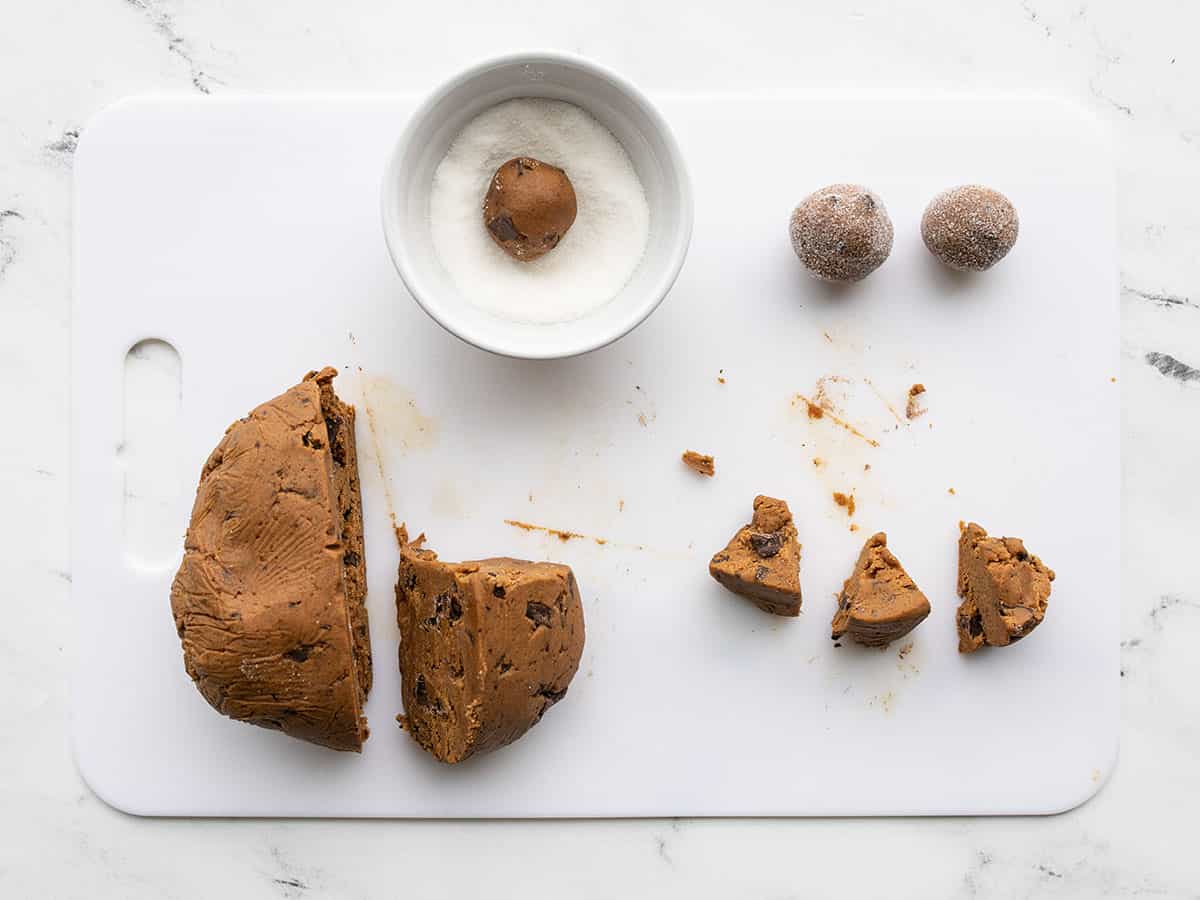 Cookie dough being shaped and rolled in sugar