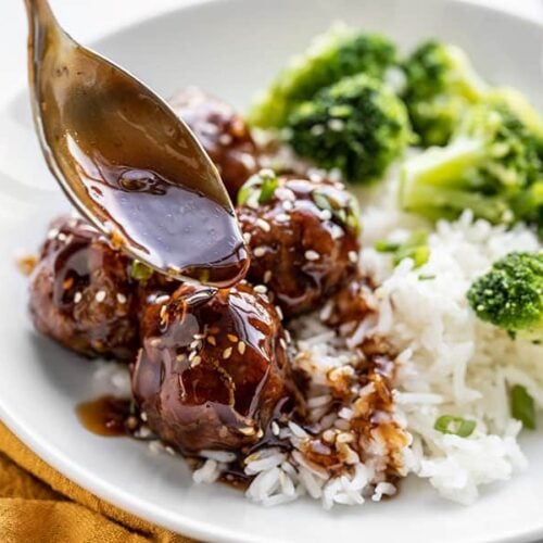 Close up of teriyaki meatball bowls with sauce being drizzled over top