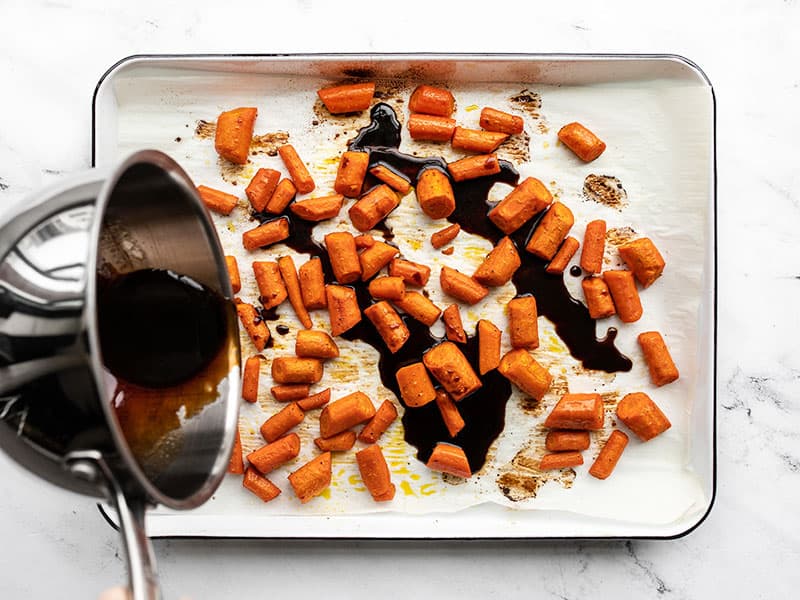 honey balsamic glaze being poured over roasted carrots