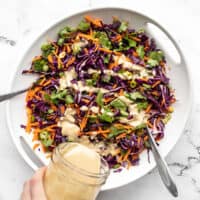 Sesame ginger dressing being poured over the crunchy cabbage salad