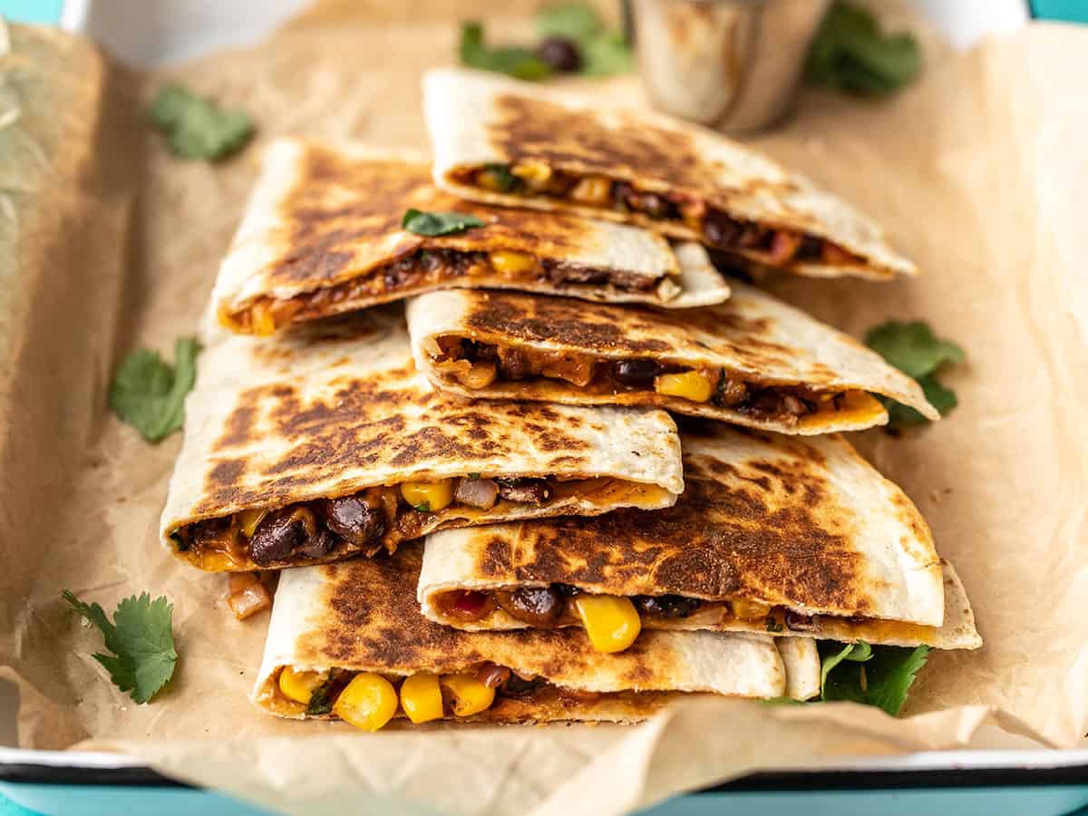 black bean quesadillas layered on a serving tray, sprinkled with cilantro