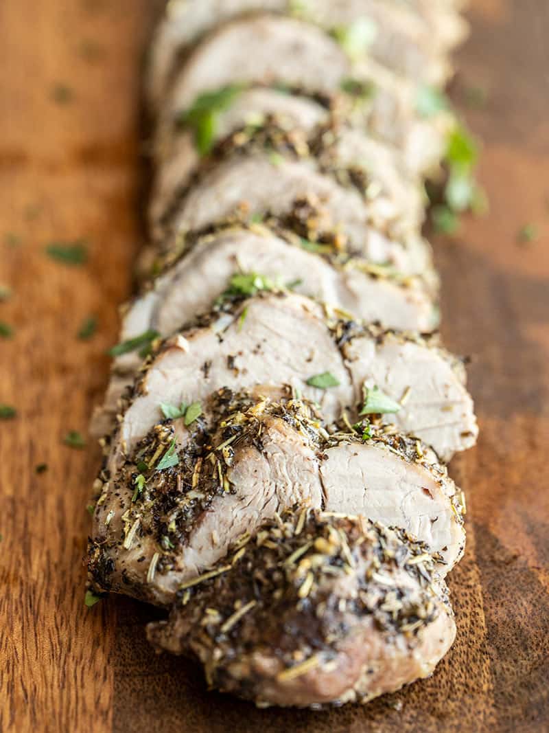 Front view of sliced Herb Roasted Pork Tenderloin on a cutting board