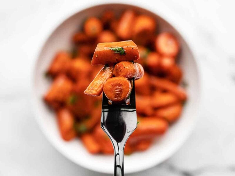 close up of a forkful of honey balsamic glazed carrots with the bowl in the background