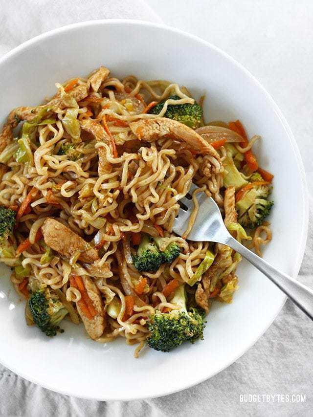 A bowl of Chicken Yakisoba with curly ramen noodles wound around the fork.