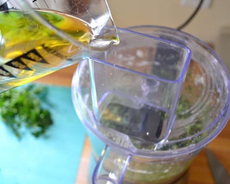 Pouring olive oil into the food processor. 