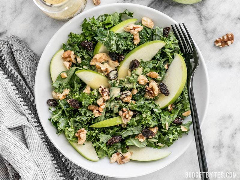 Apple Dijon Kale Salad with dressing poured over top, ready to eat