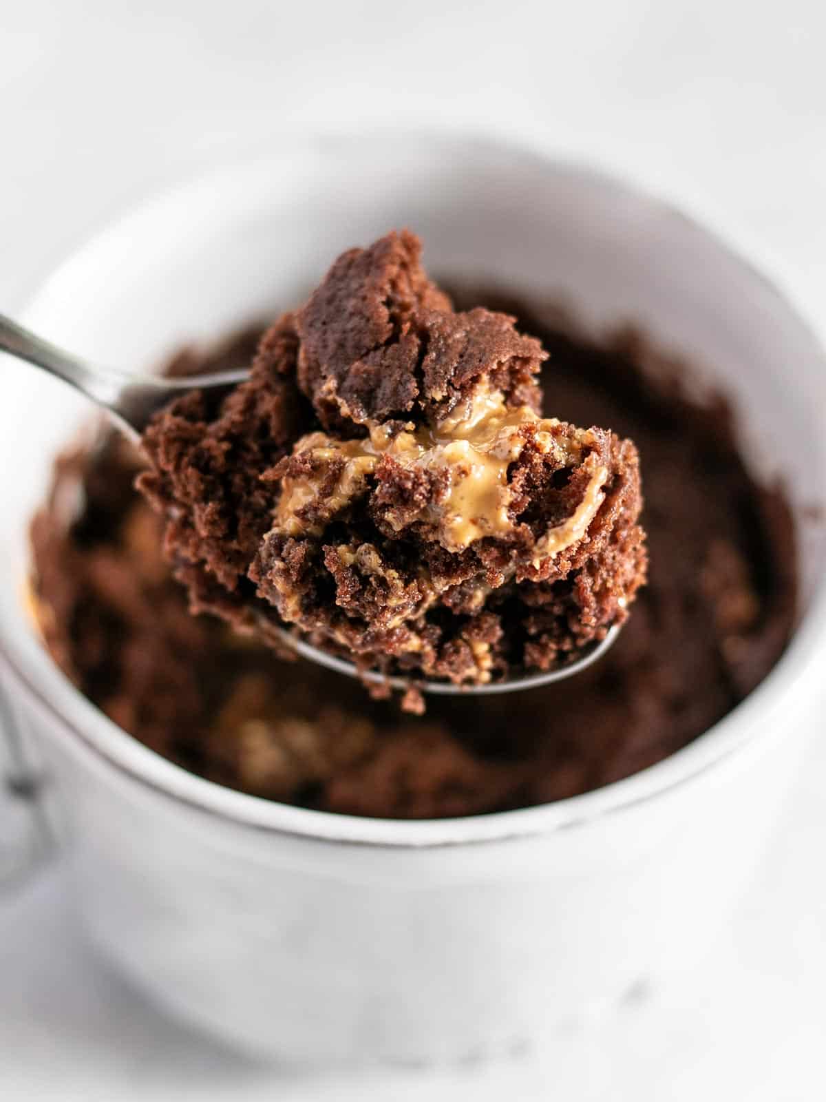 Chocolate cake being lifted out of the mug by a spoon.