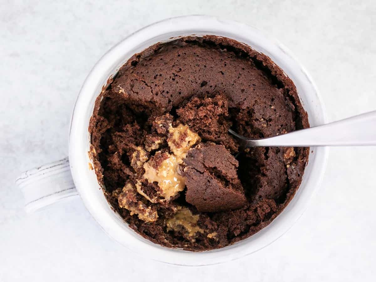 Overhead view of a chocolate mug cake with a spoon in the center.