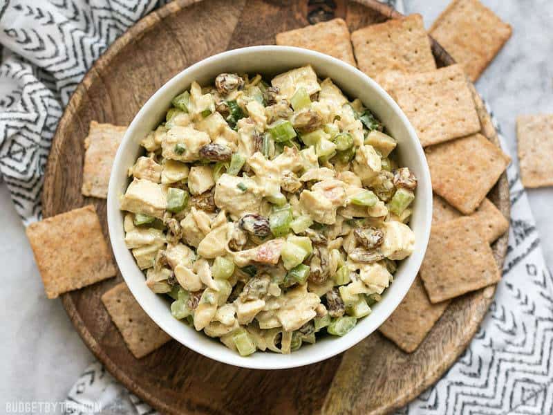 Overhead view of Curry Chicken Salad on a wooden plate with crackers. 