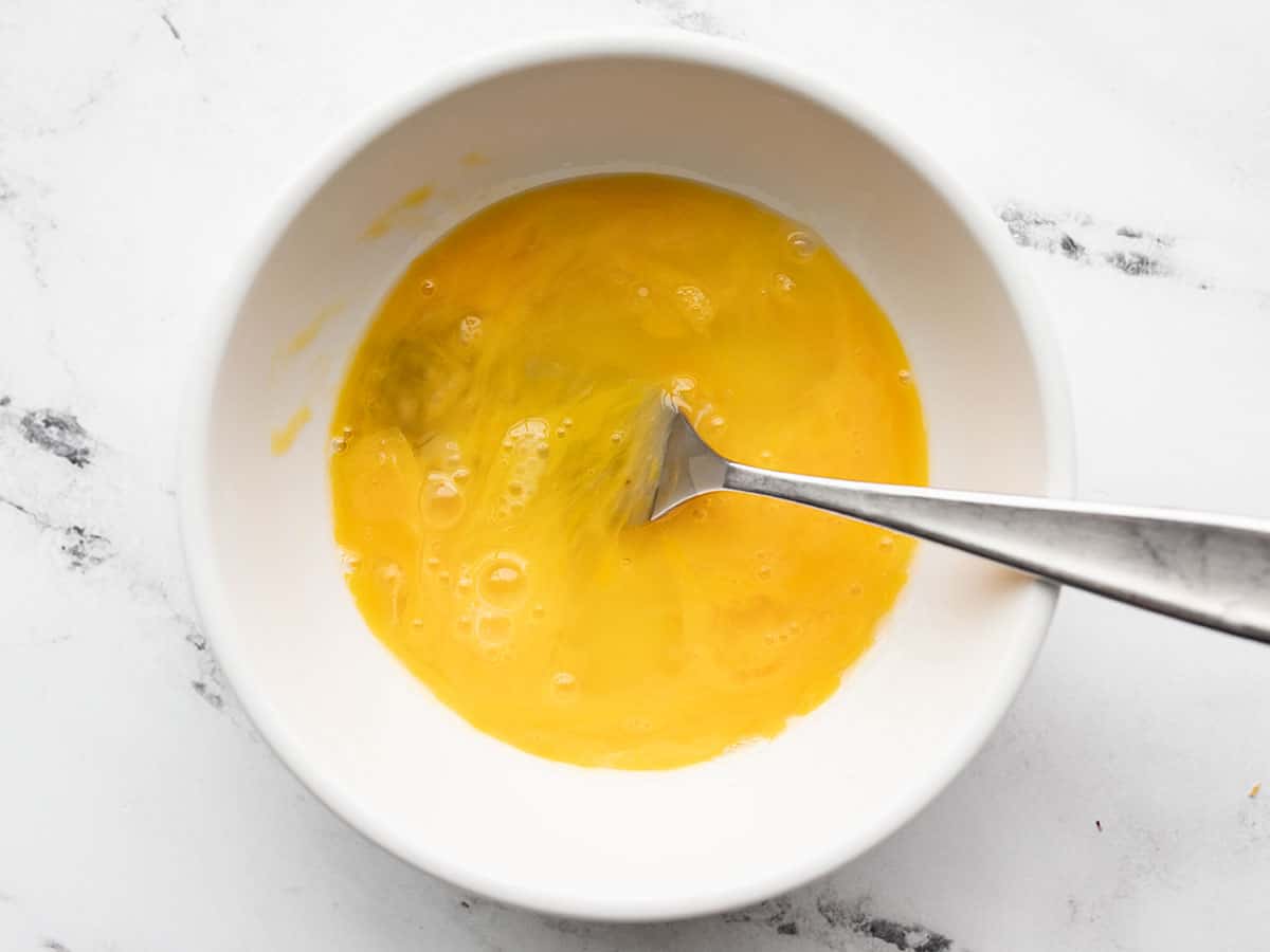 Whisked egg in a bowl with a fork