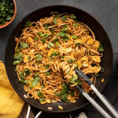 spicy sriracha noodles in a skillet with tongs