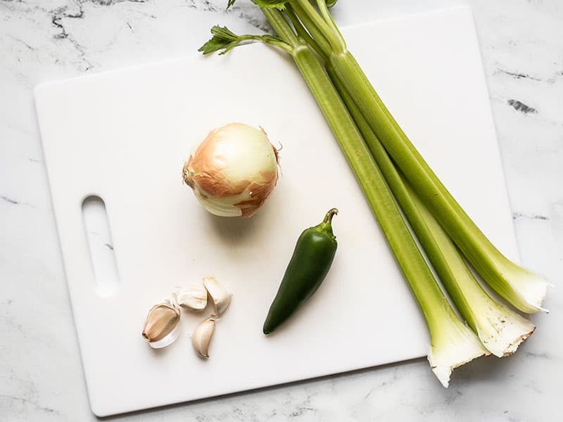 Celery, onion, jalapeño and garlic on a cutting board