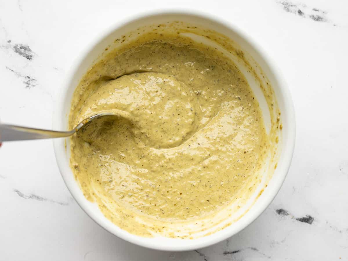 Creamy pesto dressing in a bowl being stirred