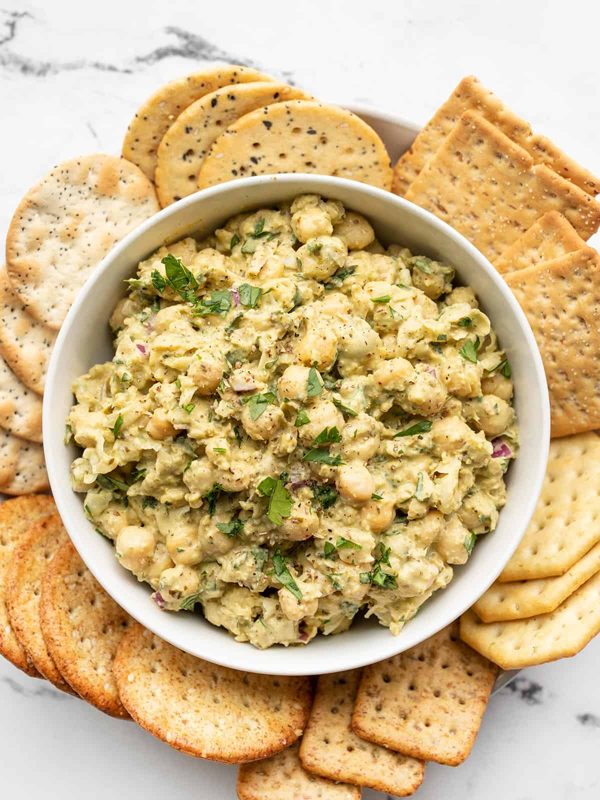 Pesto Chickpea Salad in a bowl surrounded by crackers