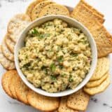Pesto chickpea salad in a bowl surrounded by crackers
