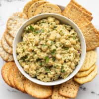 Pesto chickpea salad in a bowl surrounded by crackers