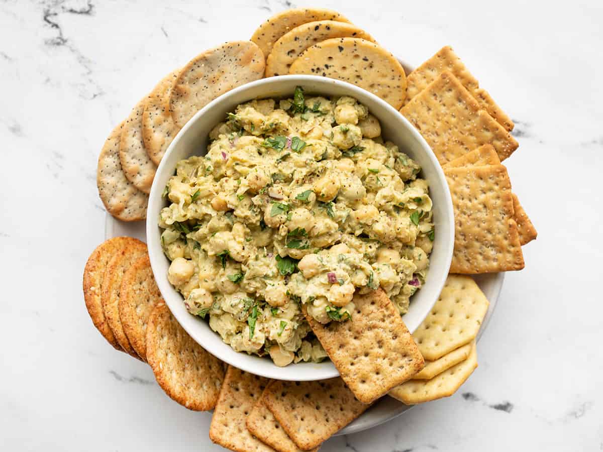 Pesto chickpea salad in a bowl with a cracker dipped into the side