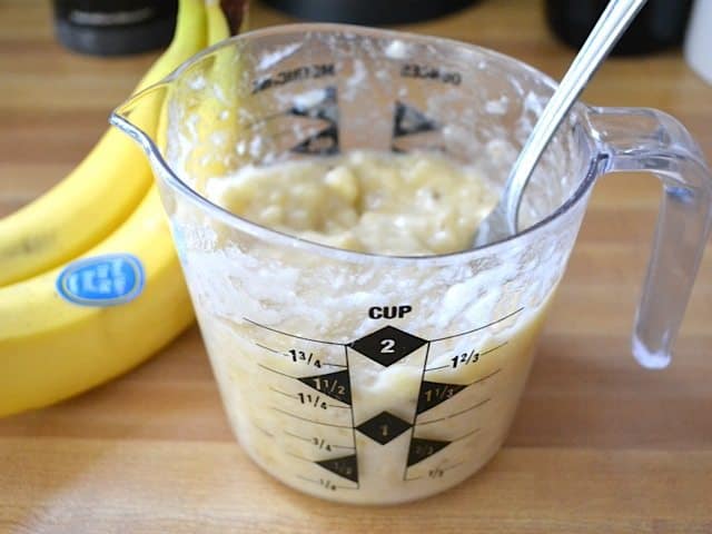 mashed bananas in measuring cup with fork 