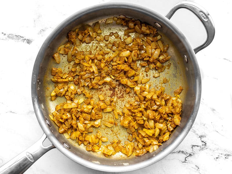 Curry powder added to the skillet with onions garlic and ginger