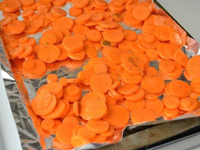 carrots spread out on baking sheet lined with tin foil, ready to bake 