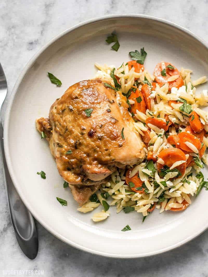 One maple dijon chicken thigh with a side of orzo salad on a plate 