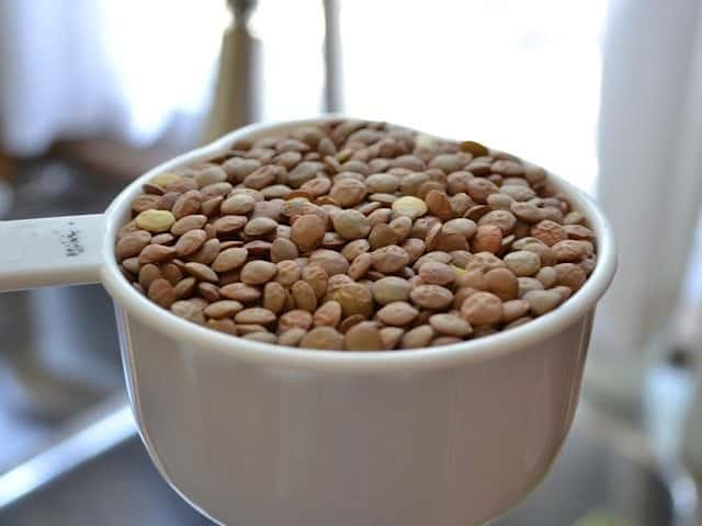 measuring cup of brown lentils