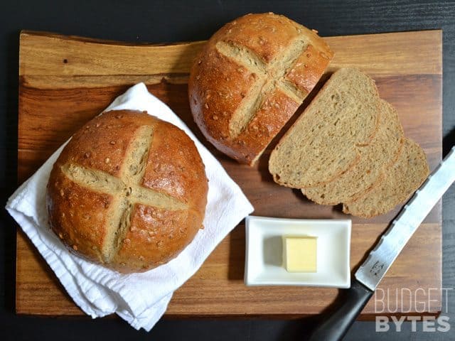 Top view of two loafs of Honey Sunflower Bread, one sliced with knife and butter on the side 