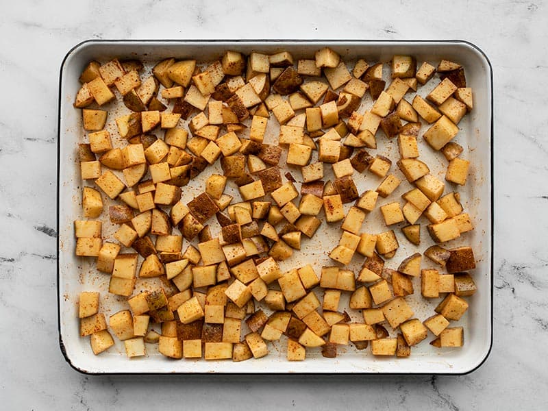 Seasoned potato cubes on a baking sheet
